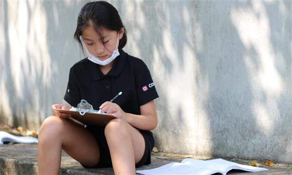 student writes on clipboard